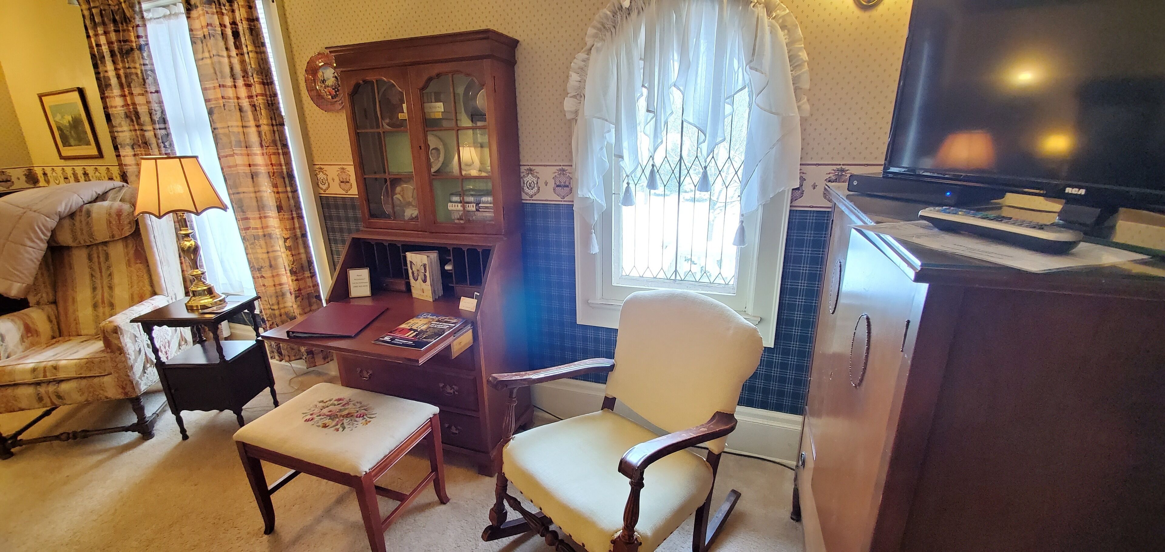 A room with a bed, a wooden cabinet, a television, and a window with curtains.