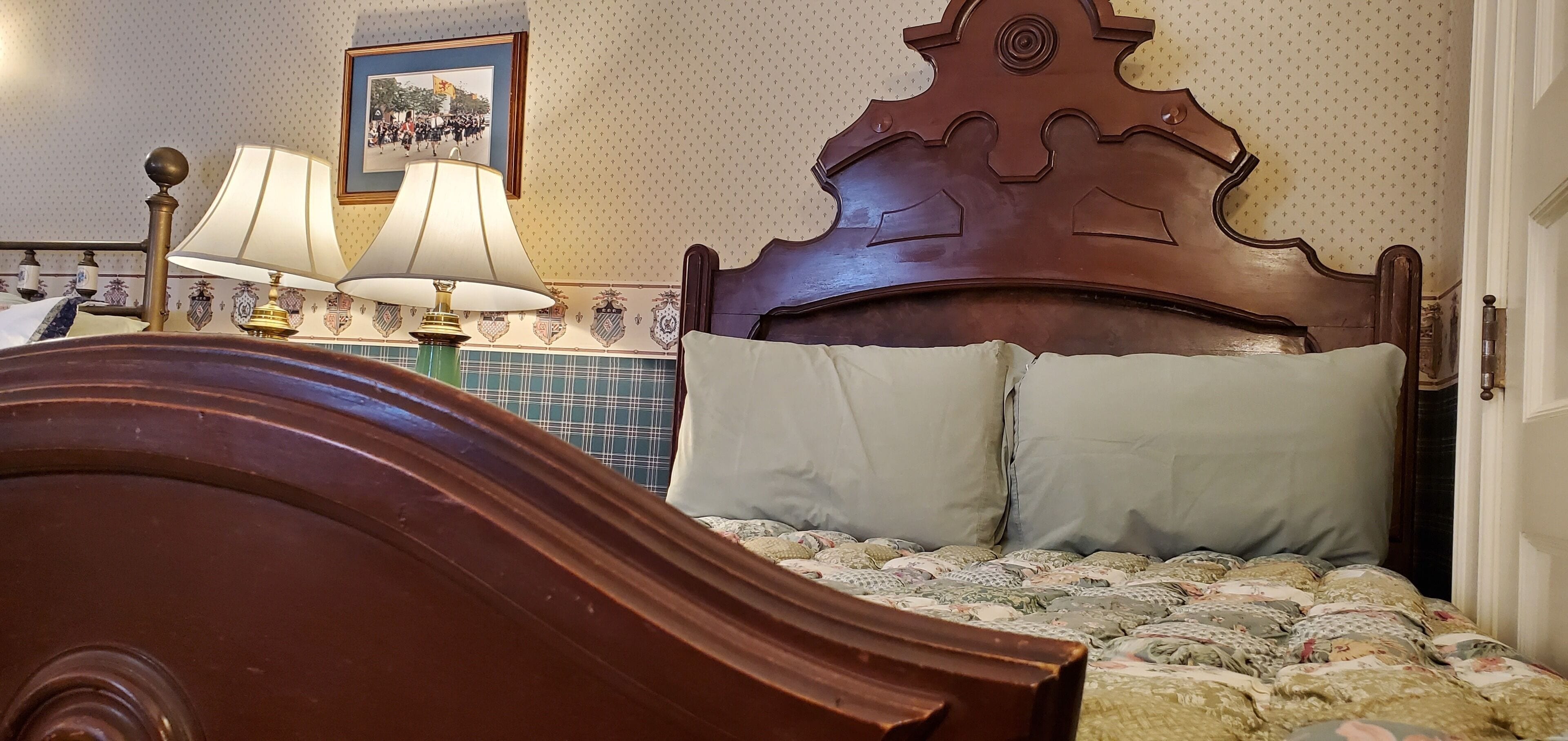 Un lit en bois avec une tête de lit, deux lampes de chevet et une couvre-lit à motifs.