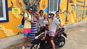 A group of people standing in front of a building with a mural, a sign indicating to keep the driveway clear, and a motorcycle parked nearby. - Vagabond - Hostel (Ko Pha-ngan)