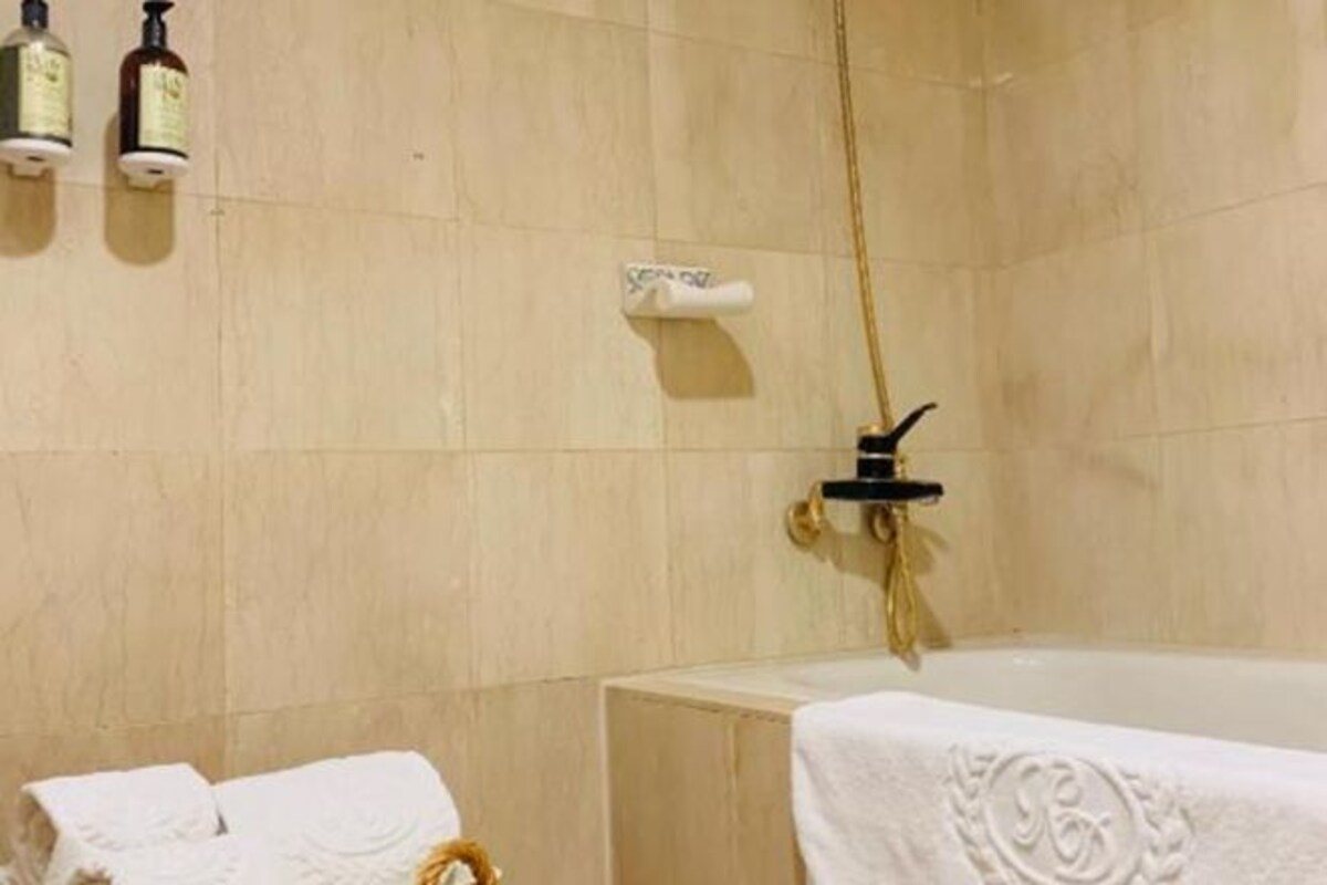 A bathroom with a bathtub, a towel rack, and a shower head.