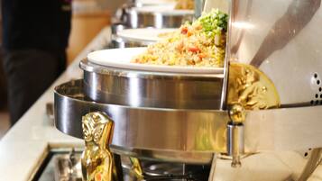 Ein Buffet mit mehreren Edelstahl-Servierschalen und einem goldfarbenen Anreißlöffel.