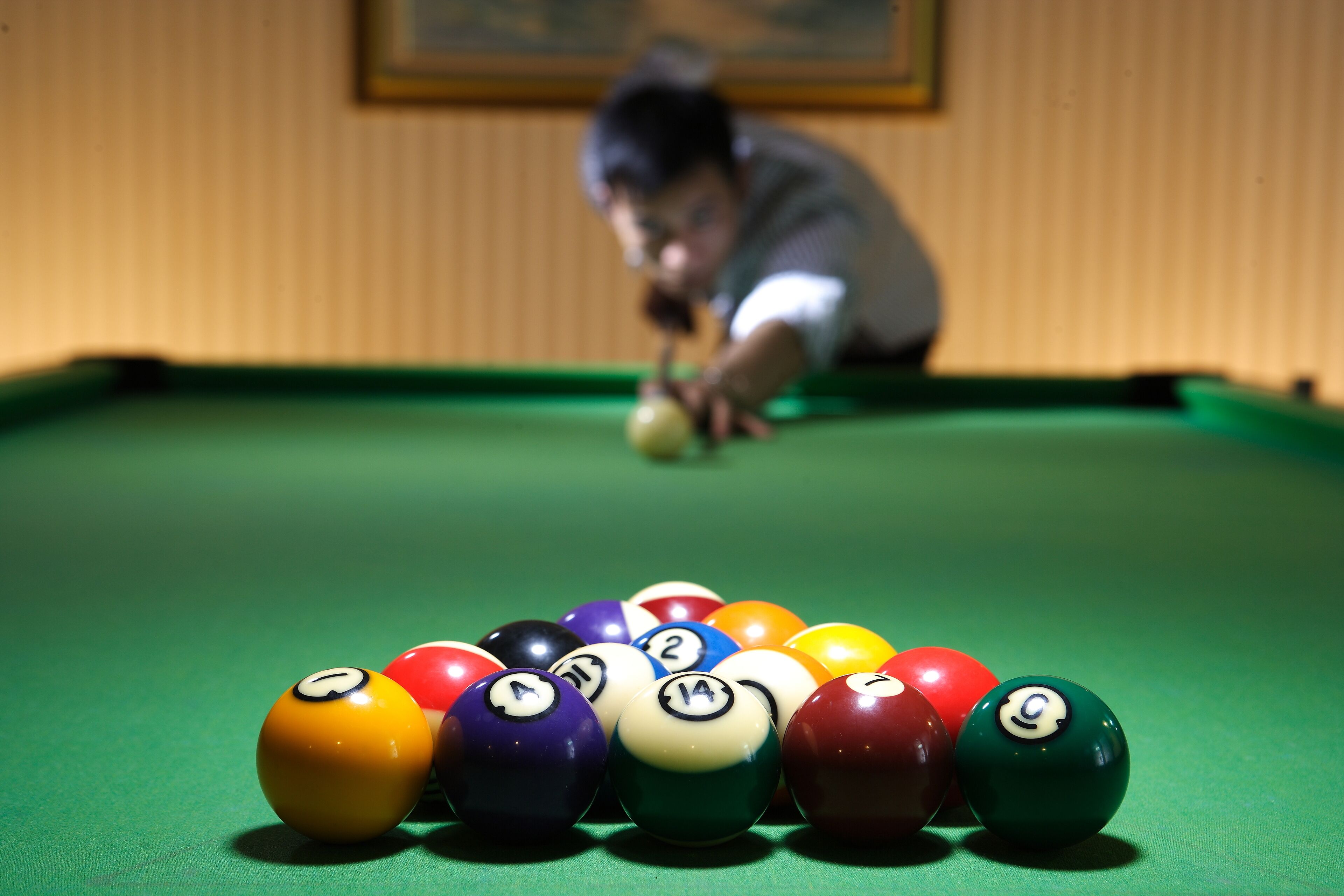 A pool table with numbered balls and a person playing.