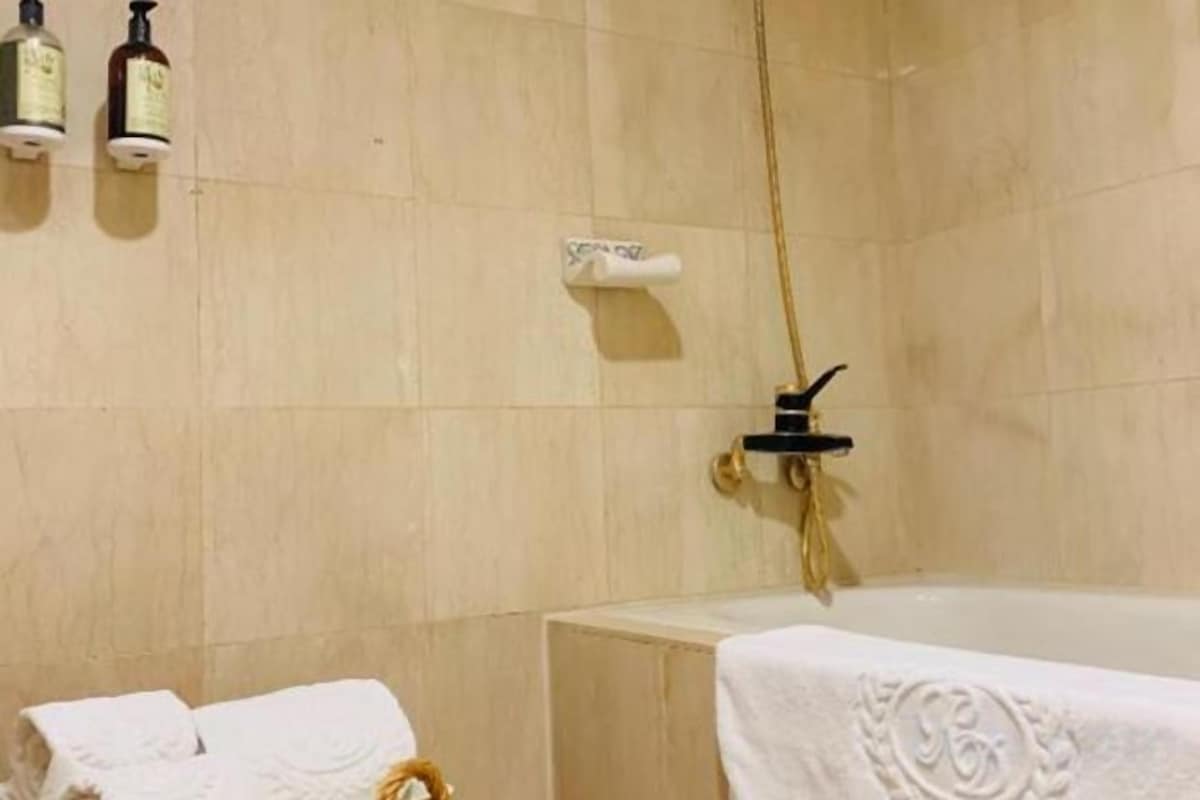 A bathroom with a bathtub, a towel rack, and a shower head.