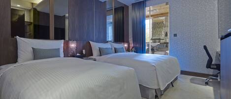 A modern hotel room with two large beds, a bathroom with a sink and mirror, and a view of the outside.