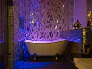 Un baño con una bañera independiente, un espejo y una pared con espejos verticales.