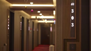 A hotel hallway with a red carpet, wooden paneling, and a number sign indicating room 303. - Beauty Hotels Taipei - Hotel Bstay (Taipei)