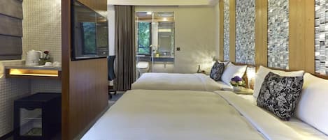 Habitación de hotel con dos camas, un escritorio con hervidor, un espejo y vistas al exterior.