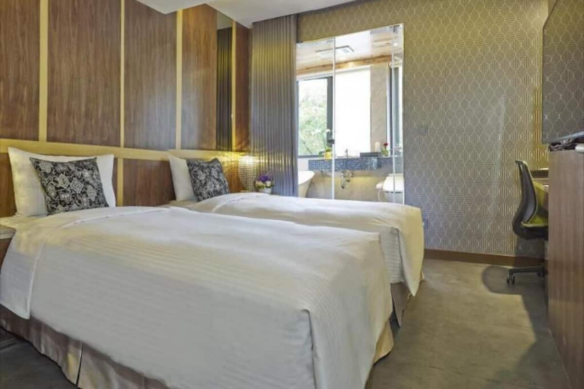 Una habitación de hotel con dos camas, un escritorio y una silla.