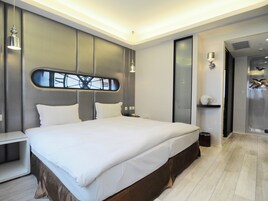 Un dormitorio moderno con una cama grande, una mesita de noche y un velador.