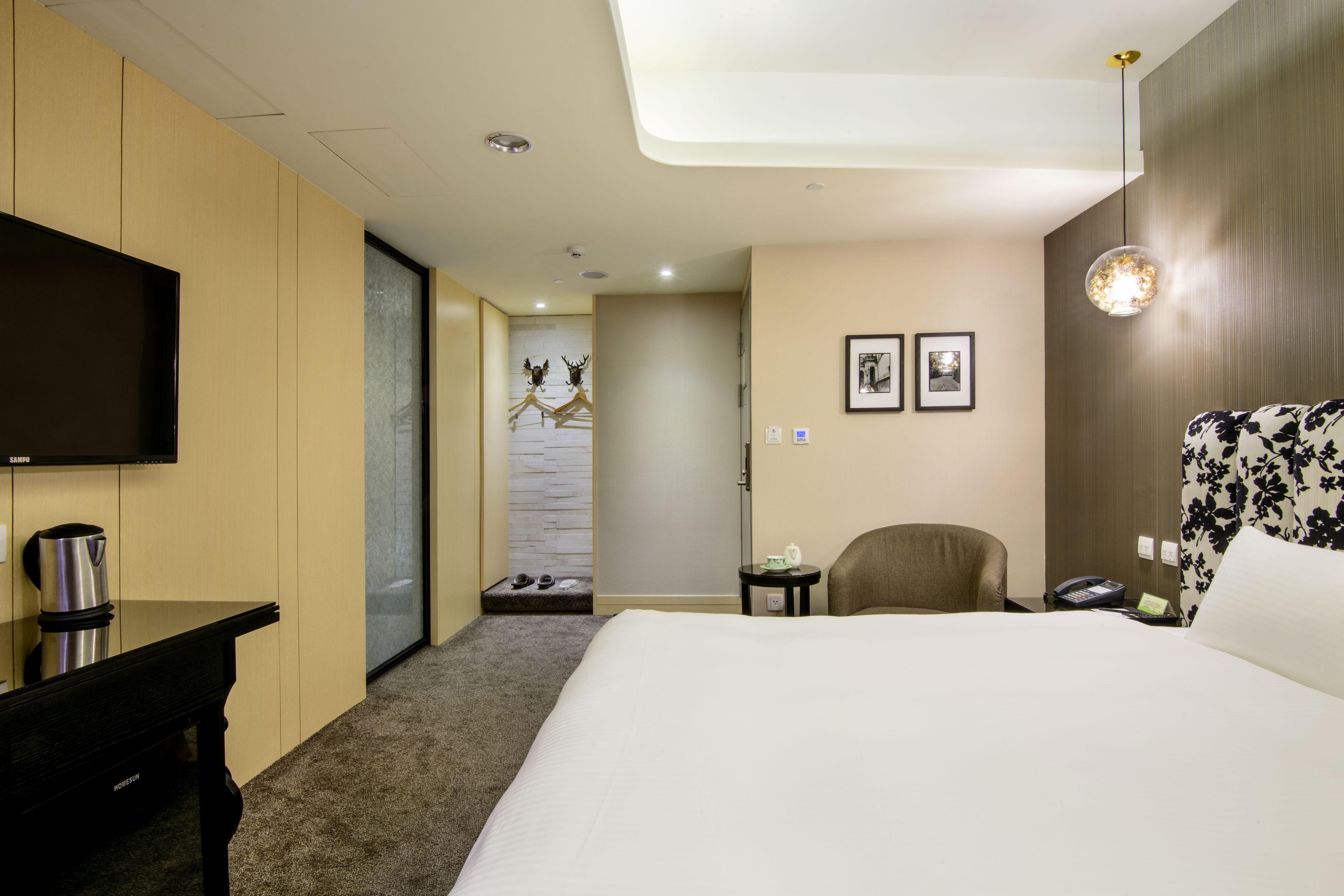 Une chambre d’hôtel équipée d’un lit, d’une télévision, d’un bureau, d’une chaise, d’une petite table et d’un téléphone fixé au mur.