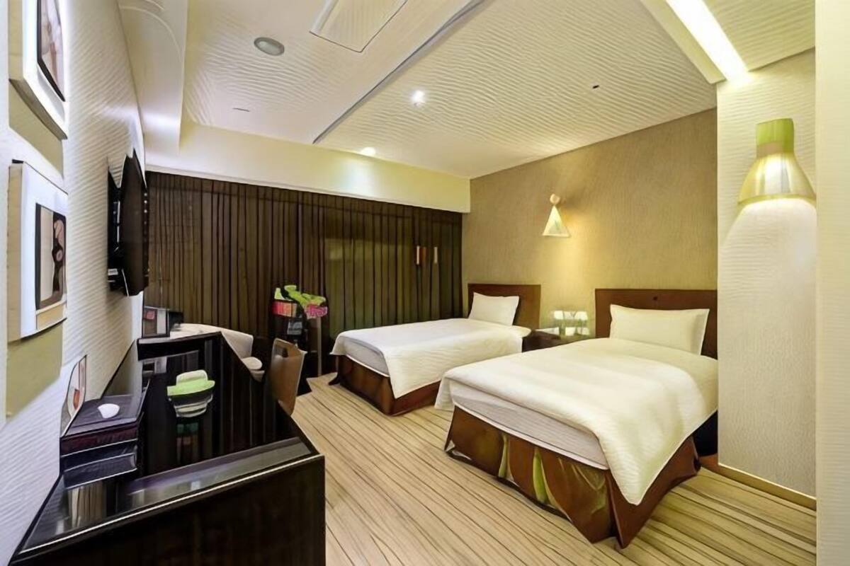Habitación de hotel con dos camas, un escritorio, un televisor y un minibar.