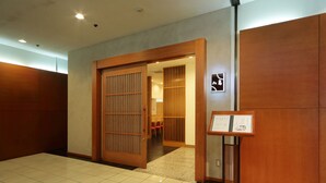 Un hall d’hôtel doté d’une porte coulissante en bois, d’un comptoir d’accueil et d’un sol carrelé.