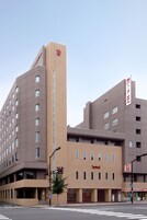 Un hôtel moderne, doté d’une enseigne verticale bien visible, de plusieurs étages et situé sous un ciel dégagé.