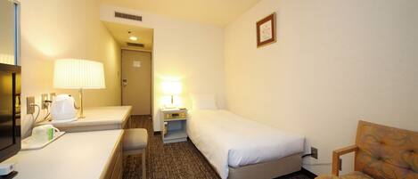 Ein Hotelzimmer mit Bett, Schreibtisch mit Lampe, Stuhl und Fernseher.