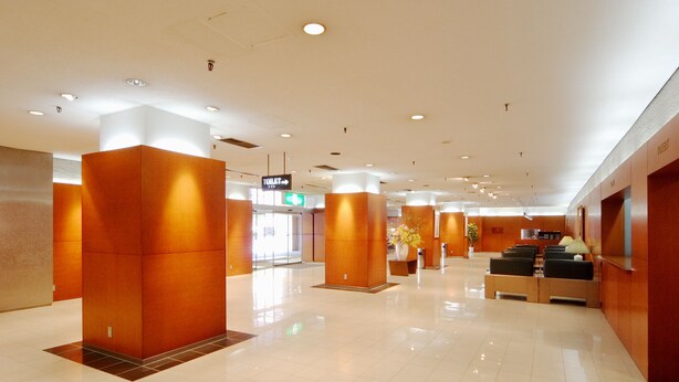 Un hall d’entrée spacieux au design moderne, comprenant un comptoir d’accueil, un espace détente et des panneaux d’orientation.