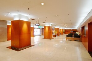 Eine großzügige Lobby mit modernem Design, ausgestattet mit einer Rezeption, einer Sitzecke und Hinweisschildern.