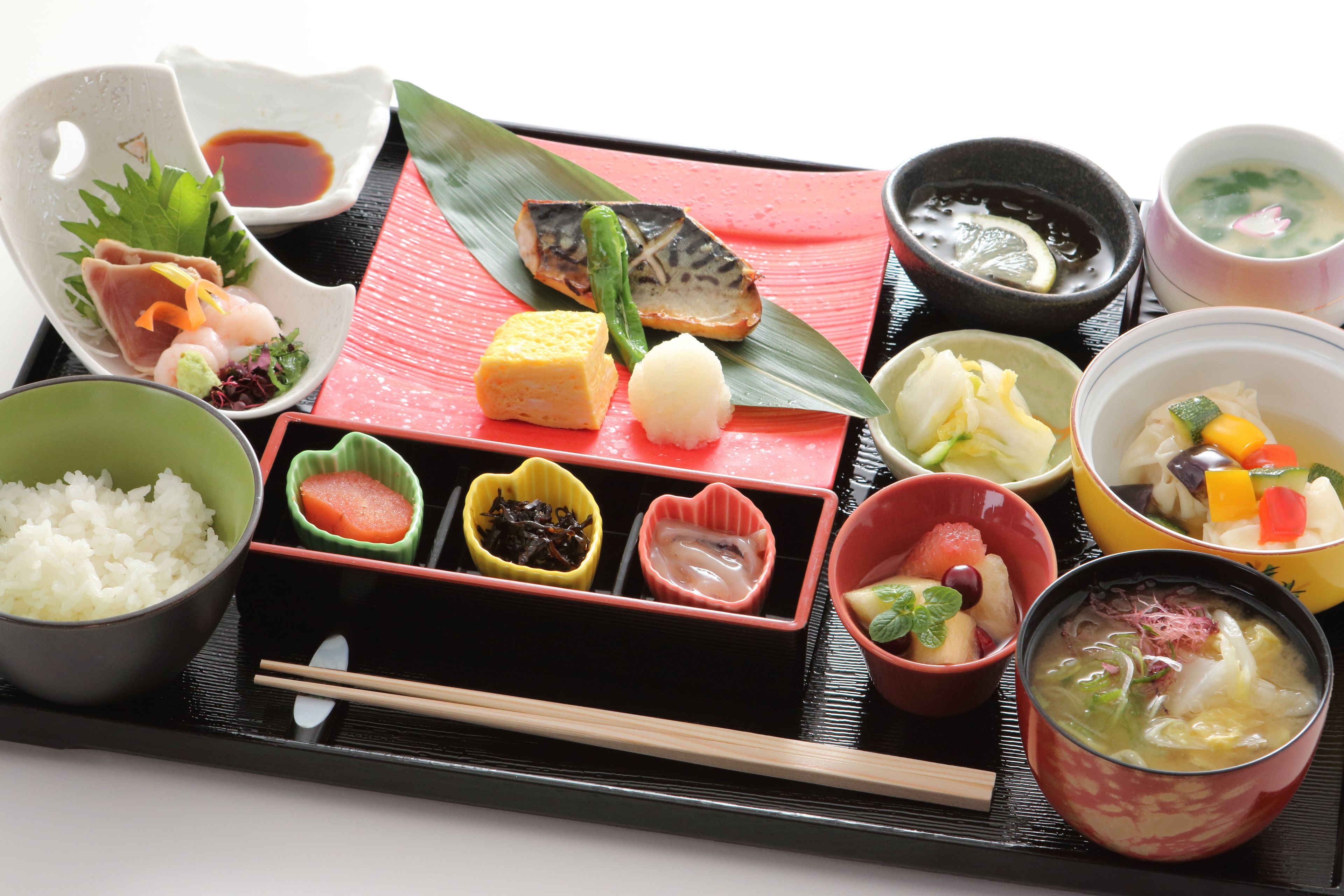 A traditional Japanese meal tray with various dishes including rice, fish, and soup.