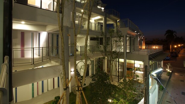 A multi-story hotel with balconies, a central courtyard, and a nighttime view.