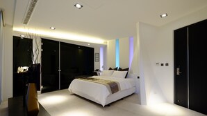 A modern bedroom with a large bed, a desk, and a wardrobe.