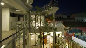 A multi-story building with glass railings, a tree, and a courtyard area.