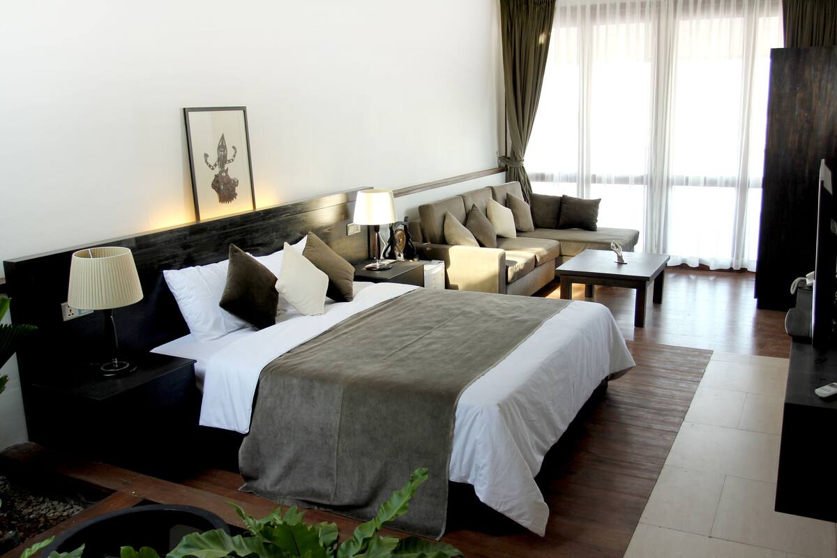 Una habitación de hotel con una cama, un sofá, un escritorio y un televisor.
