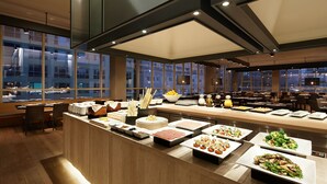 A buffet with various food items and a view of the cityscape through large windows.