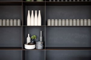 Un interior moderno y de estilo oscuro, con estantes que exhiben diversos recipientes y objetos decorativos.