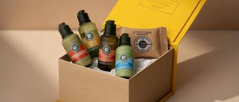 Une boîte en carton contenant des produits de la marque L’OCCITANE, notamment du shampooing, de l’après-shampooing, du gel douche et de la lotion pour le corps.