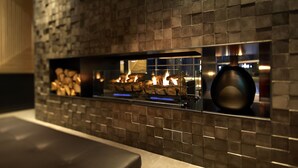 A modern fireplace with a stone facade and a visible fire.