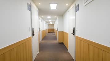 A long, narrow hallway with wooden paneling on the walls and carpeted floor.