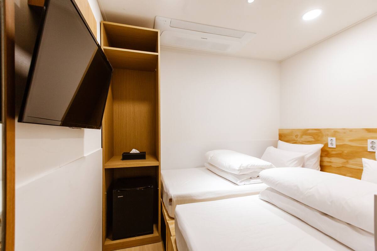 A compact hotel room with a bed, a small desk, a wardrobe, and a television.