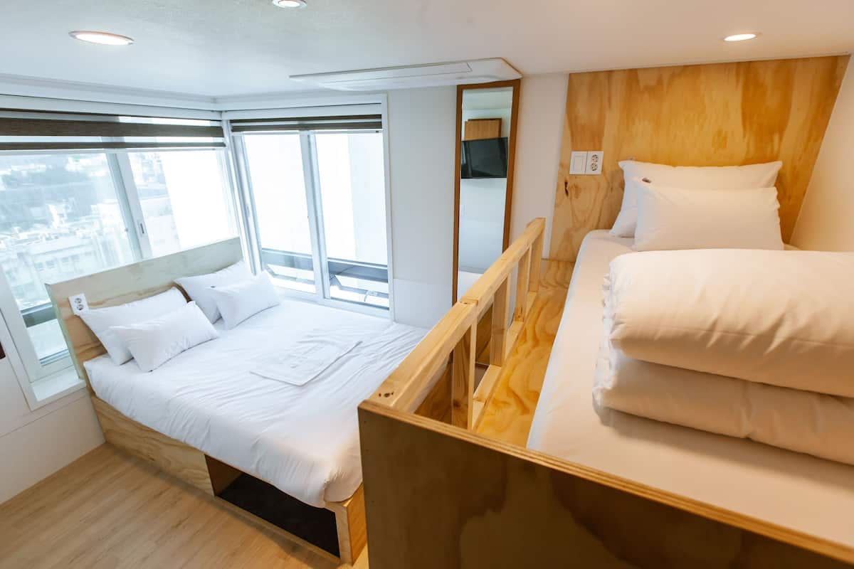 A modern hotel room with a large bed, a smaller bed, and a wooden headboard.
