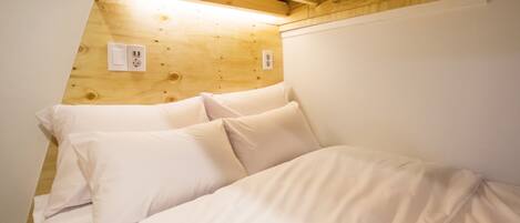 Un dormitorio con techo de madera y ropa de cama blanca.