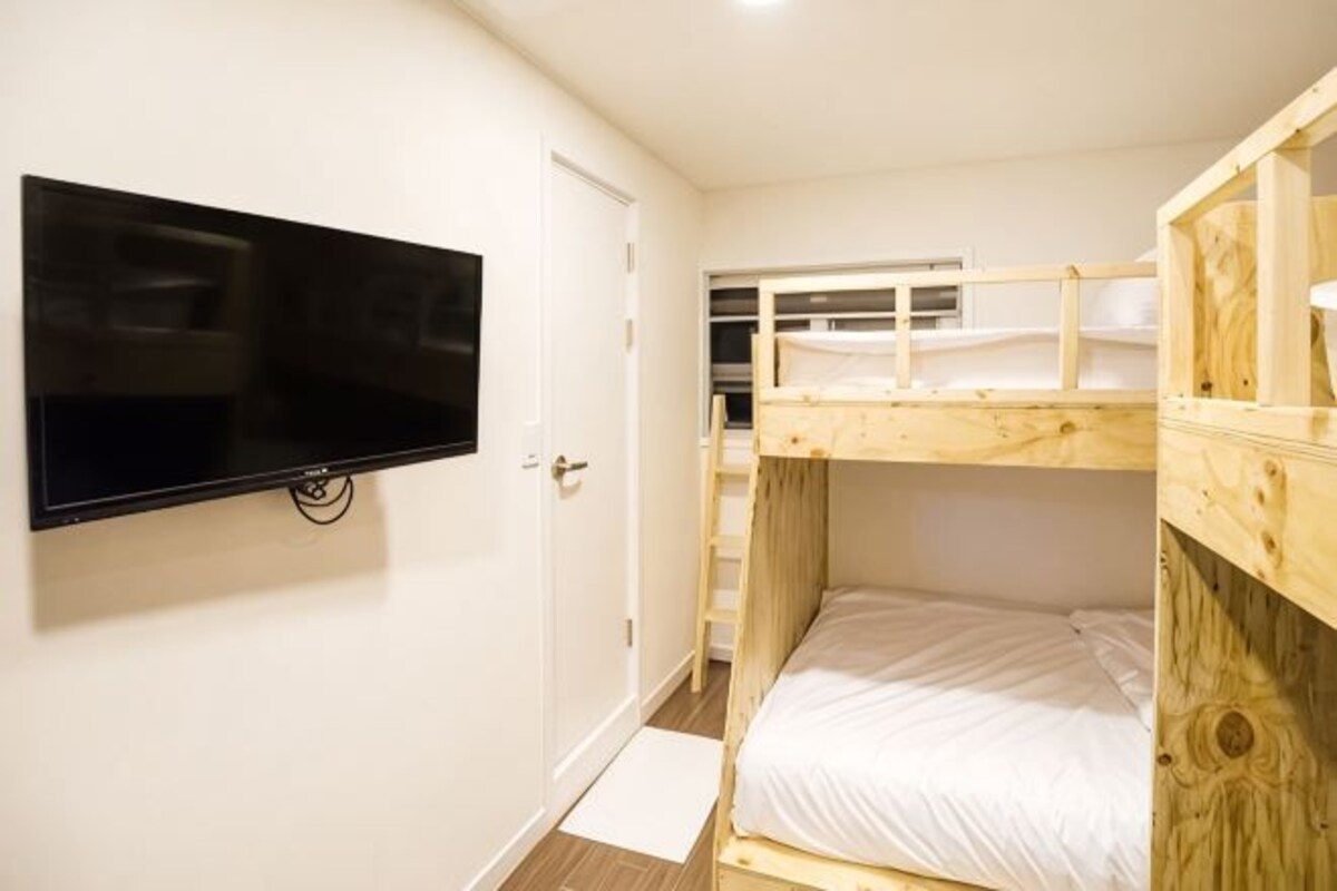 A bunk bed room with a TV mounted on the wall.
