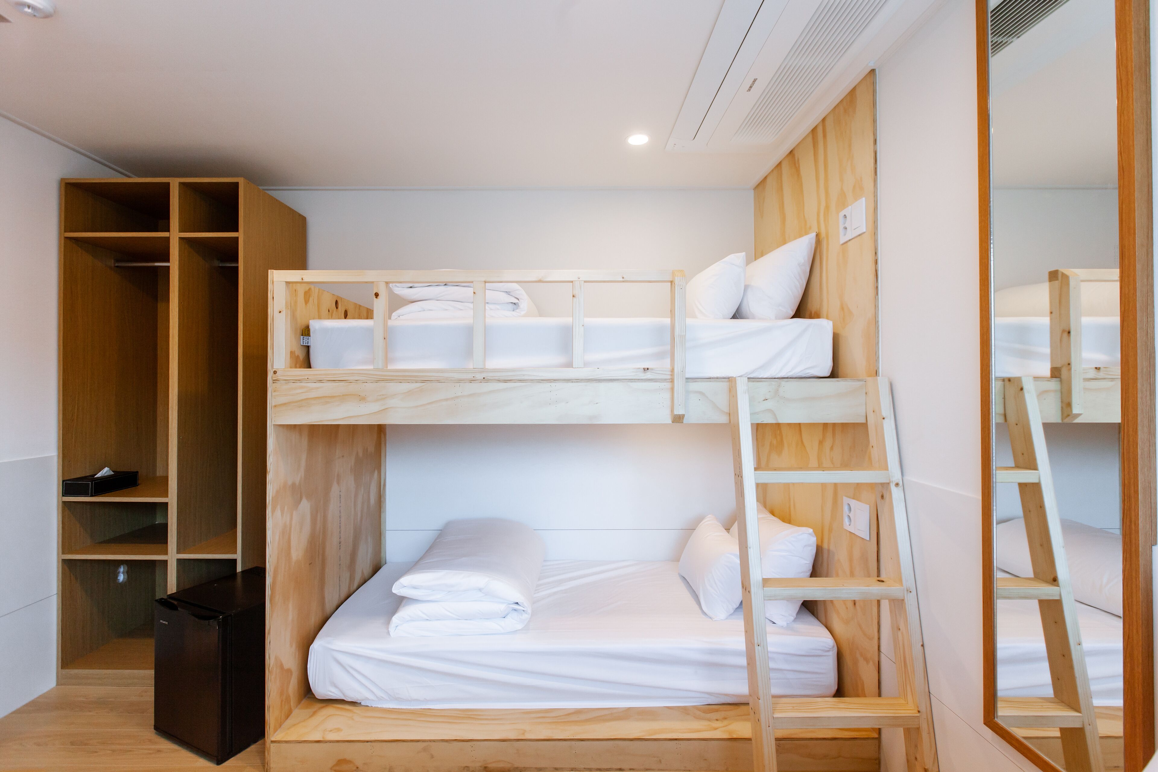 A bunk bed room with a wardrobe and a small black appliance.