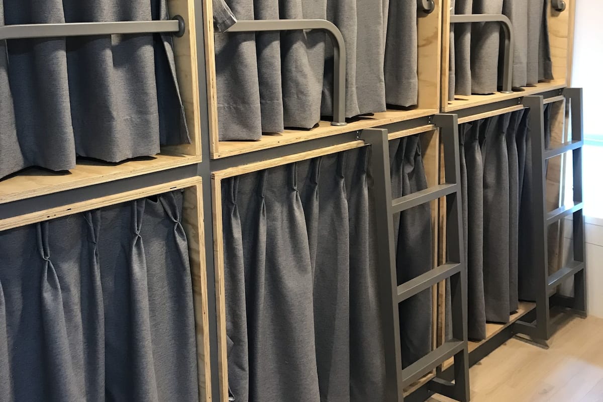 A wall of grey curtains with wooden frames and metal rods, likely in a hotel or similar accommodation.