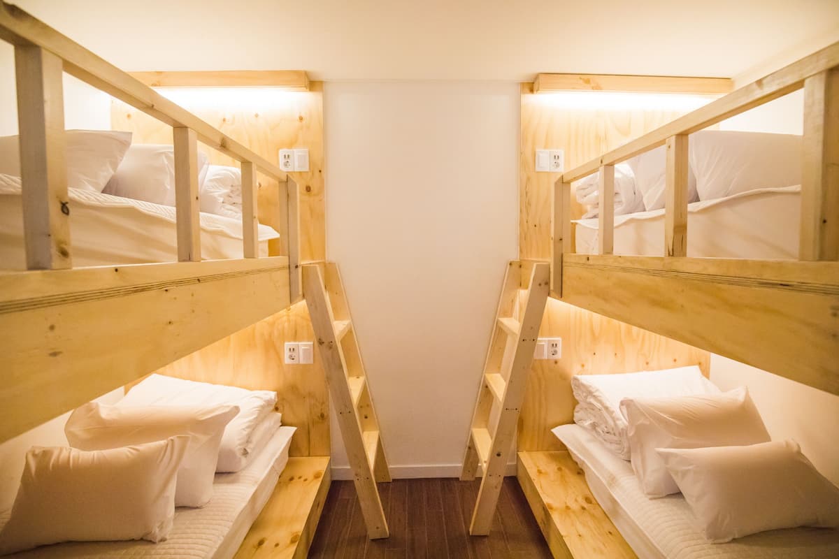 A room with two wooden bunk beds, each with a mattress and pillows.