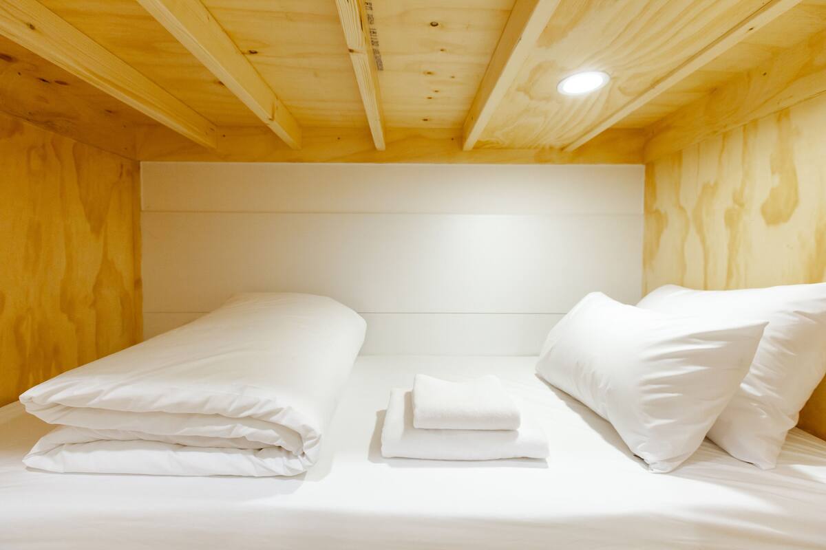 A wooden cabin-style room with a bed, pillows, and a headboard.