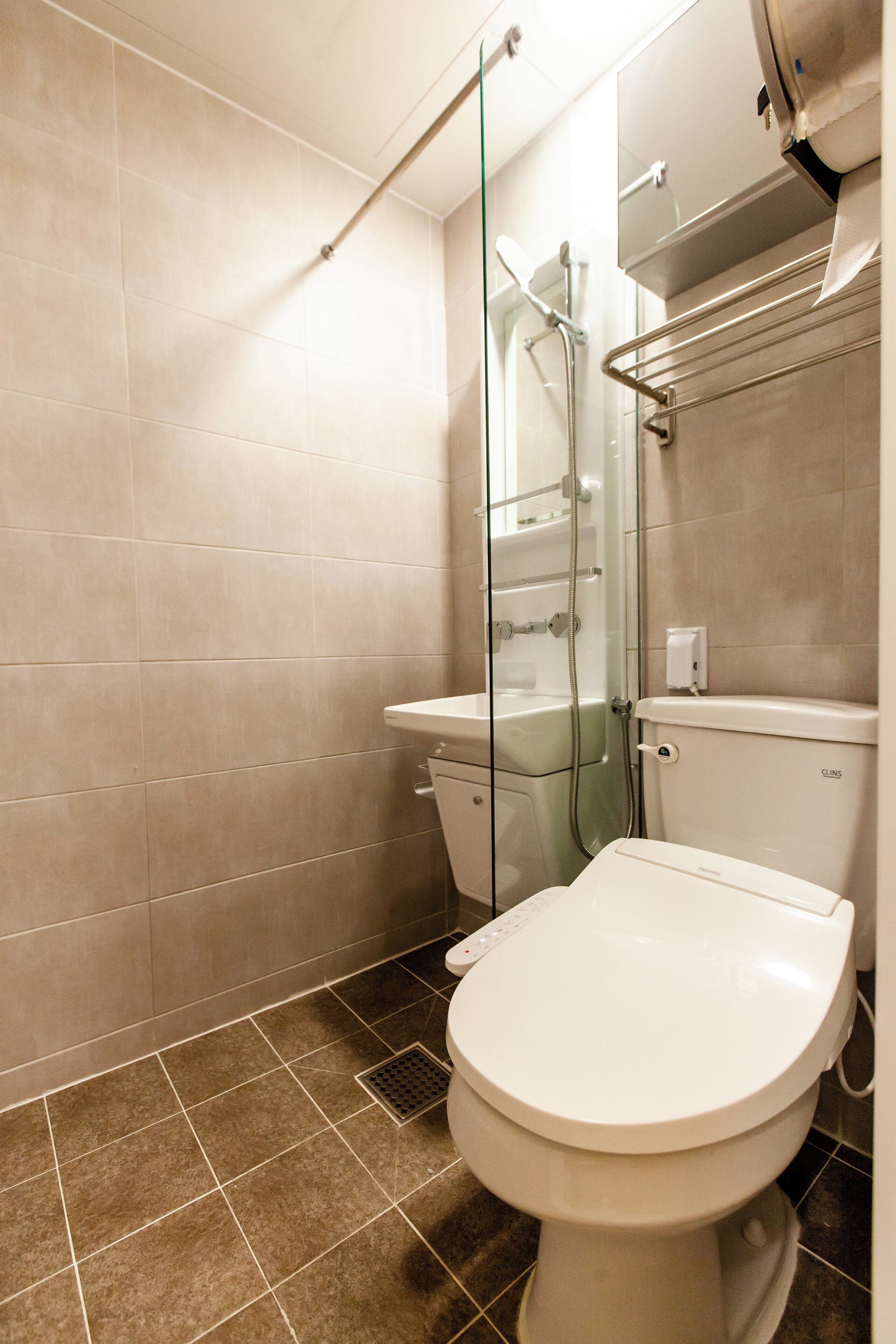 A modern bathroom with a toilet, shower, and glass-enclosed shower stall.