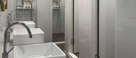 Une salle de bain moderne avec un grand lavabo, un miroir et deux cabines de douche.