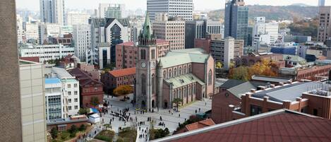 A cityscape with a prominent church, modern buildings, and a large open square.