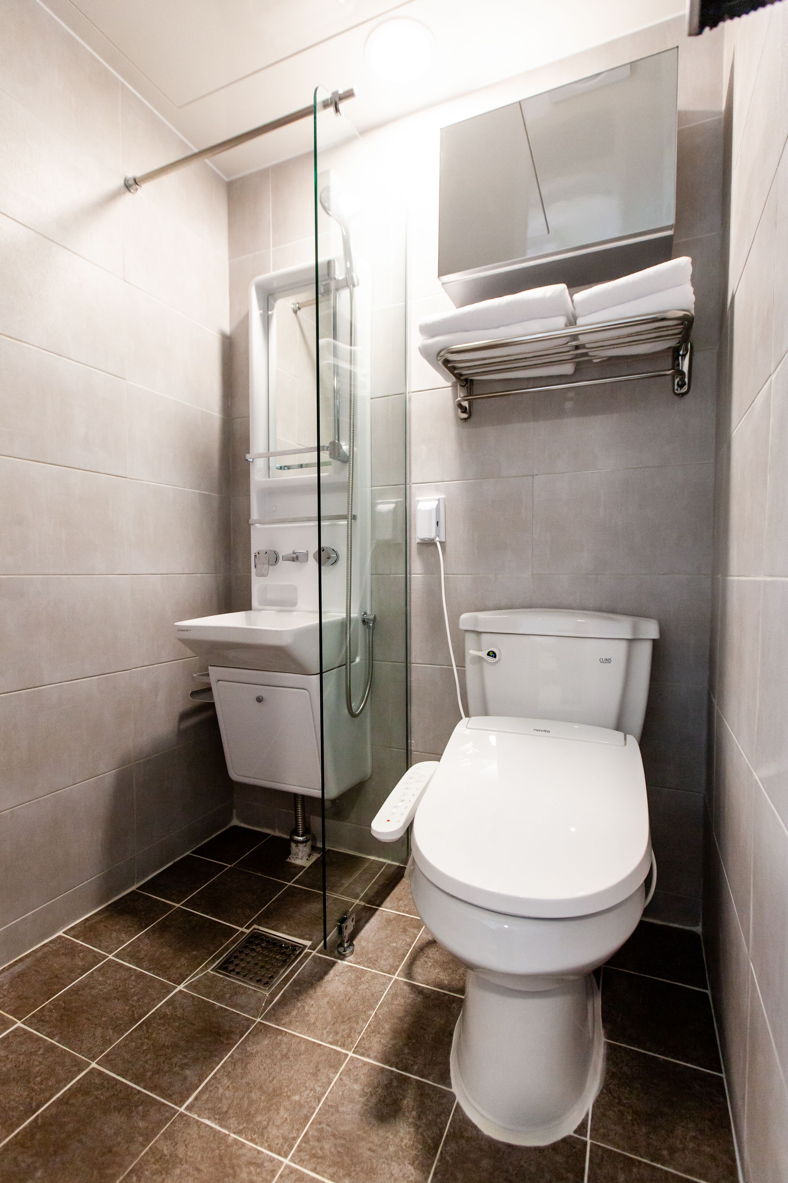 Un baño moderno con ducha de vidrio, inodoro blanco y lavamanos empotrado.