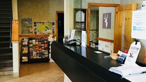 A reception area with a black counter, a map display, and a clock on the wall. - Boulder Creek Inn (Donnelly)