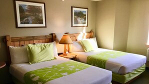 A hotel room with two beds, each with green and white bedding, wooden headboards, and framed pictures on the walls. - Boulder Creek Inn (Donnelly)