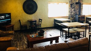 A cozy indoor seating area with a television, a stone wall, and a fireplace. - Boulder Creek Inn (Donnelly)
