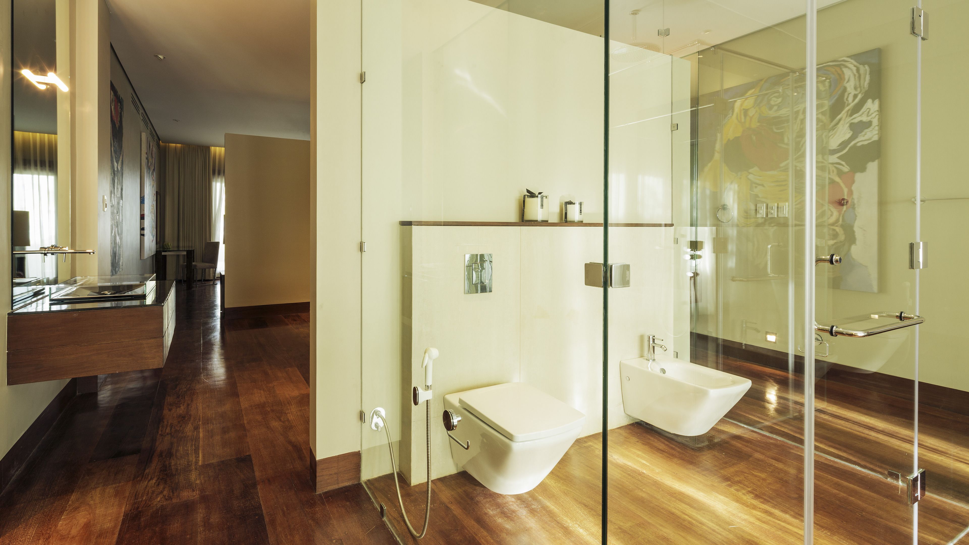 Un baño moderno con cabina de ducha de vidrio, un bidé y un tocador con espejo.