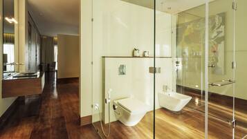 Un baño moderno con cabina de ducha de vidrio, un bidé y un tocador con espejo.