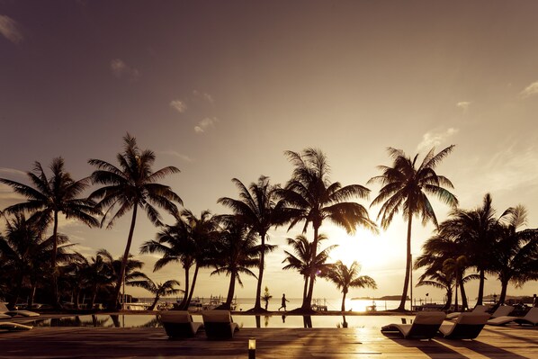 Eine Strandlounge mit Palmen und Blick auf den Sonnenuntergang.