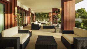 A modern outdoor lounge area with wicker furniture, a central coffee table, and potted plants.