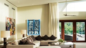 A modern living room with a sectional sofa, a glass coffee table, and a large window with a view of greenery.